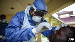 Mhudumu wa hospitali akimpima mtu mmoja COVID-19 katika maabara ya Kenya Medical Research Institute (KEMRI) huko Kisumu, magharibi mwa Kenya, Apr. 23, 2020.