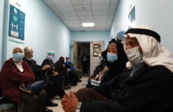 FILE - People wait their turn to receive a COVID-19 vaccine, at a vaccination center in the Jordanian capital Amman, Jan. 13, 2021.