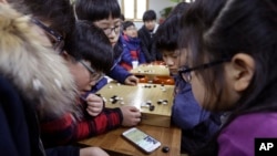 Anak-anak TK mengamati HP sambil belajar memainkan Baduk, di Pusat Pelatihan Baduk (Lee's Baduk Center) di Seoul, Korea Selatan, 15 Maret 2016. (AP Photo/Ahn Young-joon)