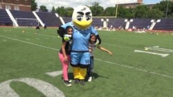Two refugees girls take a photo with DC United's mascot, Talon. (June Soh)
