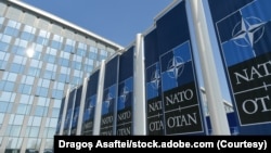 FILE -- NATO logo flags in front of the headquarters building in Brussels, Belgium.