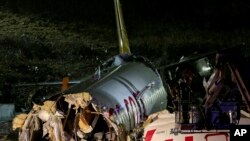 Rescue members and firefighters work after a plane skidded off the runway at Istanbul's Sabiha Gokcen Airport, Istanbul, Feb. 5, 2020.