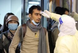 Passengers coming from China wearing masks to prevent transmission of a new coronavirus are checked by Saudi Health Ministry employees upon their arrival at King Khalid International Airport, in Riyadh, Saudi Arabia, Jan. 29, 2020.