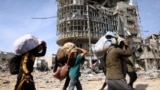 FILE - Displaced Palestinians carry their belongings as they walk amid the devastation upon their return to central Rafah in the southern Gaza Strip on Jan. 19, 2025, after a ceasefire between Israel and the Hamas movement took effect.