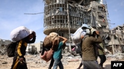 FILE - Displaced Palestinians carry their belongings as they walk amid the devastation upon their return to central Rafah in the southern Gaza Strip on Jan. 19, 2025, after a ceasefire between Israel and the Hamas movement took effect.