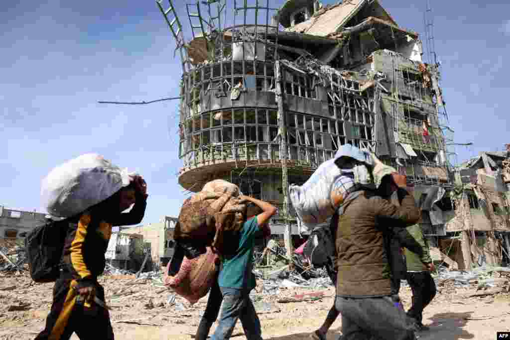 Displaced Palestinians carry their belongings as they walk amid the devastation upon their return to central Rafah in the southern Gaza Strip on Jan. 19, 2025, after a ceasefire between Israel and the Hamas movement took effect.