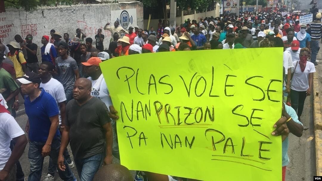 Ribuan demonstran melakukan unjuk rasa di Port-au-Prince, Haiti, hari Minggu (9/6) dengan tulisan yang artinya: "Para Pencuri (koruptor) tempatnya di penjara, bukan di Istana (Presiden)."