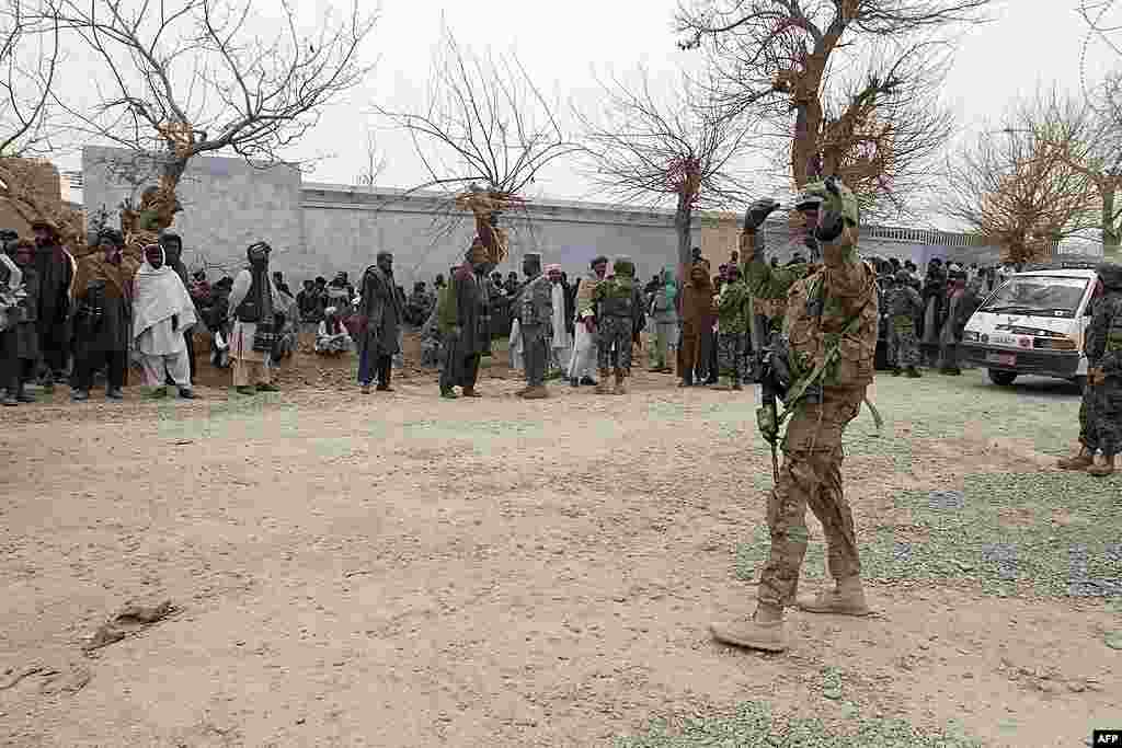 A U.S. Army soldier directs traffic as Afghan citizens gather in Panjwai. (AP)