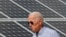FILE - Joe Biden, then U.S. vice president, walks past solar panels while touring the Plymouth Area Renewable Energy Initiative in Plymouth, New Hampshire, June 4, 2019.