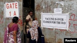 A policeman asks people who came to receive a dose of a coronavirus disease (COVID-19) vaccine to leave as they stand outside the gate of a vaccination center which was closed due to unavailability of COVID-19 vaccine supply, in Mumbai, May 3, 2021.