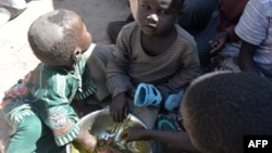 FILE - Children eat on November 13, 2014 in a camp for Nigerian refugees in Minawao, in the extreme north-west of Cameroon. 