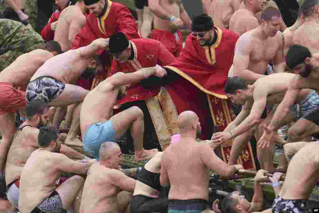 Priests pull Christian Orthodox believers out from the cold water, who follow the Julian calendar and celebrate Epiphany on Jan. 19, after swimming to retrieve a cross of the Danube river in Belgrade, Serbia.