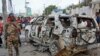 A member of the security forces walks past a wrecked vehicle outside the Elite Hotel in Mogadishu, SomaliaAug. 17, 2020.