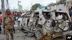 A member of the security forces walks past a wrecked vehicle outside the Elite Hotel in Mogadishu, SomaliaAug. 17, 2020.