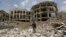 A Houthi militant walks in front of a government compound, destroyed by recent Saudi-led air strikes, in Yemen's northwestern city of Amran July 27, 2015.