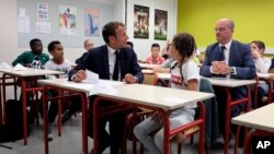 French president Emmanuel Macron looks at Jean-Michel Blanquer, minister of National Education, as they sit in a classroom of a secondary school in Laval, western France, Sept. 3, 2018, at the start of the school year in France.