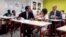 French president Emmanuel Macron looks at Jean-Michel Blanquer, minister of National Education, as they sit in a classroom of a secondary school in Laval, western France, Sept. 3, 2018, at the start of the school year in France.