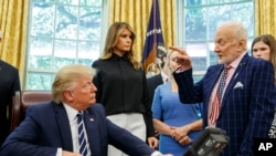 President Donald Trump listens to Apollo 11 astronaut Buzz Aldrin, right, with Vice first lady Melania Trump, during a photo opportunity commemorating the 50th anniversary of the Apollo 11 moon landing in the Oval Office of the White House, Friday.