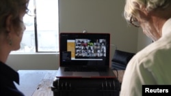 FILE - University of California professors Lisa Wymore and Greg Niemeyer look at the Zoom screen showing students in their online Collaborative Innovation course in Berkeley, March 12, 2020.