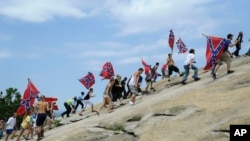 FILE - Confederate flag supporters climb Stone Mountain to protest of what they believe is an attack on their Southern heritage during a rally at Stone Mountain Park in Stone Mountain, Georgia, Aug. 1, 2015.