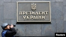 A photographer takes a picture of a sign reading "President of Ukraine" at the entrance to the presidential administration building in Kyiv Feb. 22, 2014.