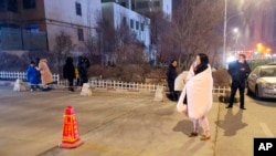 In this photo released by China's Xinhua News Agency, people stand on the street after an earthquake in Xining in northwestern China's Qinghai Province, Jan. 8, 2022.
