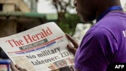 A man reads the front page of a special edition of The Herald newspaper about the crisis in Zimbabwe with the headline 'No military takeover - ZDF' on Nov. 15, 2017 in Harare.