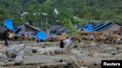 Warga memeriksa rumah-rumah mereka pasca banjir dan tanah longsor di Sentani, Papua Minggu 17/3 (Foto. Antara/Gusti Tanati via Reuters).