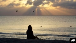 ARCHIVO - Una mujer medita en la playa de Miami Beach, Florida, el 28 de abril de 2010.