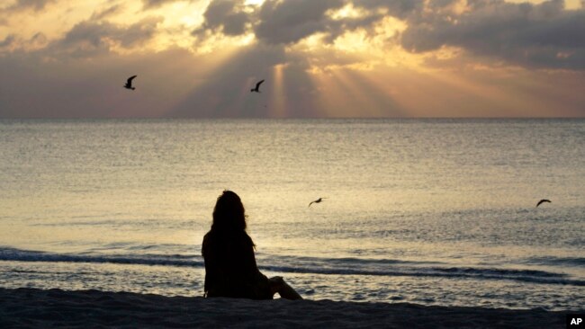 ARCHIVO - Una mujer medita en la playa de Miami Beach, Florida, el 28 de abril de 2010.