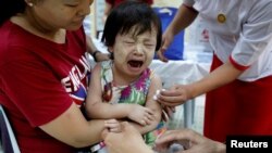 FILE - A child reacts after receiving a measles-rubella vaccination. 