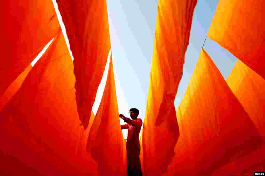 A worker dries fabrics after applying color at a dye factory in Narayanganj, Bangladesh.