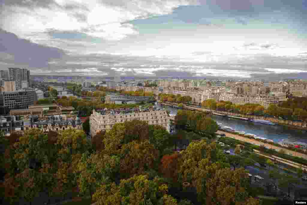 Trees start to show autumn colors in an aerial view which shows the Seine River and the skyline in Paris, France.