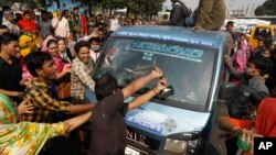 Demonstran merusak sebuah mobil dalam aksi protes buruh garmen di Savar, pinggiran Dhaka, Bangladesh, Rabu (9/1).