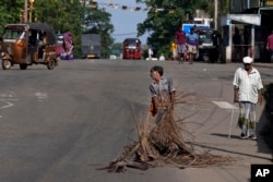 A man pulls fallen leaves to be used as firewood during a shortage of cooking gas along a usually busy road in Colombo, Sri Lanka on June 23, 2022. (AP Photo/Eranga Jayawardena)