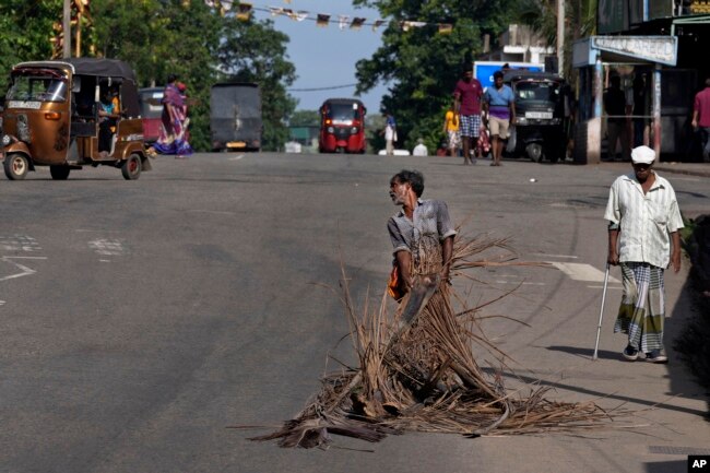 A man pulls fallen leaves to be used as firewood during a shortage of cooking gas along a usually busy road in Colombo, Sri Lanka on June 23, 2022. (AP Photo/Eranga Jayawardena)