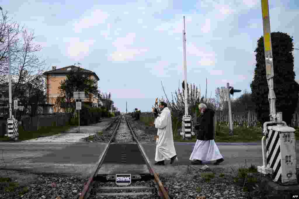 Priests Don Giuseppe Arnaudo (R), and Don Kresimir Busic, holding a crucifix, conduct a countryside procession to bless houses against the coronavirus pandemic, March 25, 2020, in Manta, Italy.