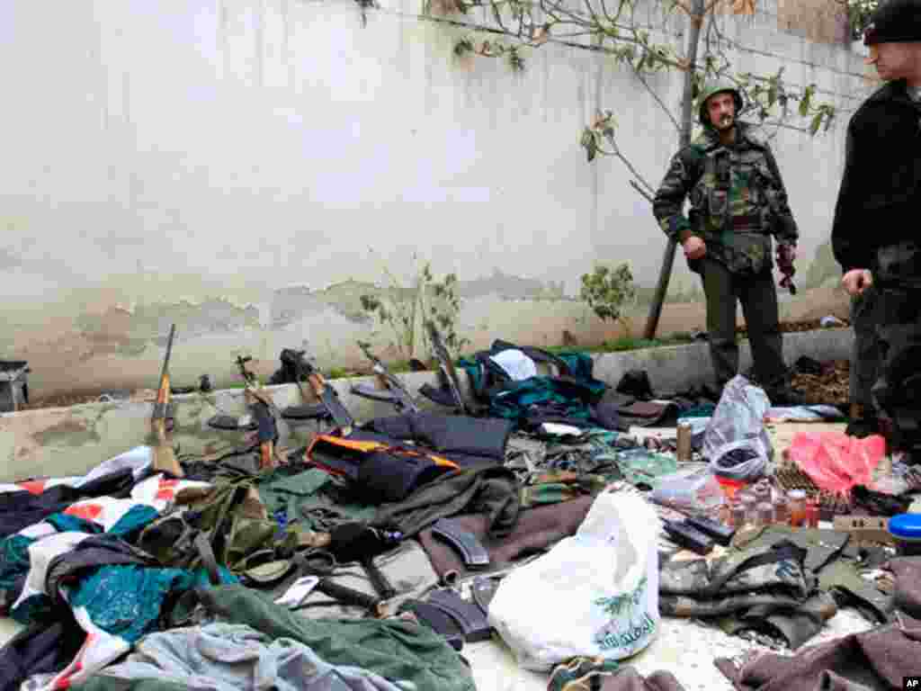A Syrian soldier displays weapons officials say were confiscated from gun men, during the tour of Arab monitors outside Damascus in Harasta, January 26, 2012. (Reuters)