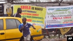 People pass by Ebola virus health warning signs, in the city of Monrovia, Liberia, Aug. 17, 2014. 