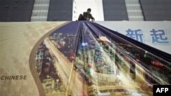 Công nhân treo một tấm quảng cáo khổng lồ trên tòa nhà chọc trời tại trung tâm thương mại ở Bắc Kinh