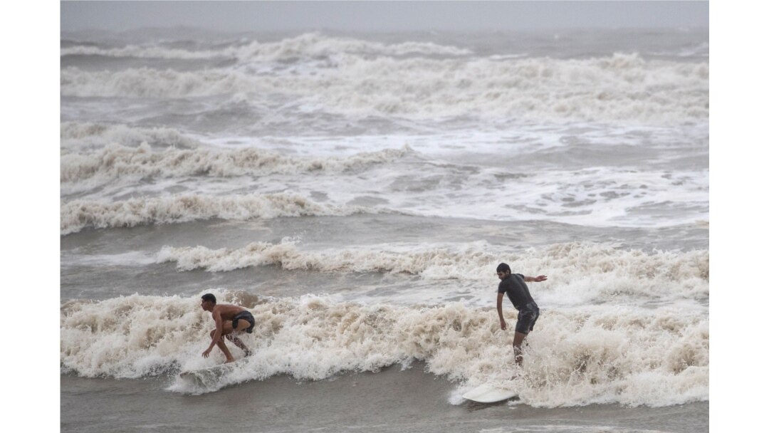 Residentes locales en Galveston, Texas, surfean en las altas olas creadas por la tormenta tropical Hanna. Julio 26 de 2020.
