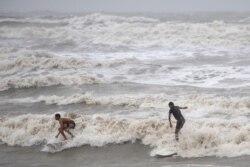 Residentes locales en Galveston, Texas, surfean en las altas olas creadas por la tormenta tropical Hanna. Julio 26 de 2020.