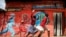 FILE - Children run past an informational mural warning people about the dangers of COVID-19 in the Kibera slum of Nairobi, Kenya, June 3, 2020.