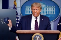 President Donald Trump holds a face mask as he speaks during a news conference at the White House, July 21, 2020.