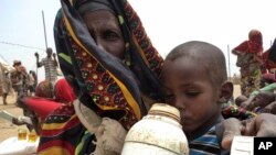 A mother quenches her child's thirst while waiting for food handouts at a health center in drought-stricken remote Somali region of Eastern Ethiopia, also known as the Ogaden, July 9, 2011.
