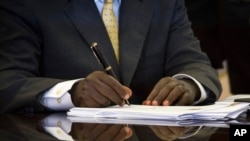 FILE - Uganda's President Yoweri Museveni signs a new anti-gay bill that sets harsh penalties for homosexual sex, in Entebbe, Uganda, Feb. 24, 2014.