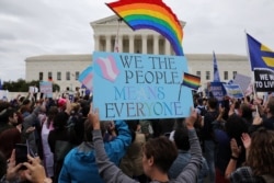 FILE - LGBTQ activists and supporters hold a rally outside the U.S. Supreme Court as it hears arguments in a major LGBTQ rights case, in Washington, Oct. 8, 2019.