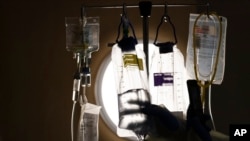 FILE - A nurse checks on IV fluids while talking to a COVID-19 patient at Providence Holy Cross Medical Center in Los Angeles, Dec. 13, 2021. 