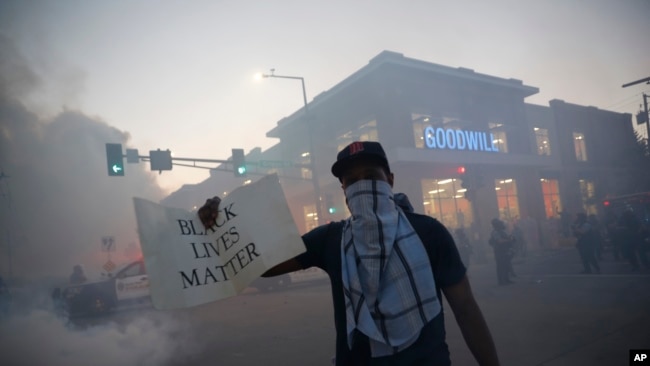A demonstrator displays a "Black Lives Matter" sign Thursday, May 28, 2020, in St. Paul, Minn. Protests over the death of George Floyd, a black man who died in police custody, broke out in…