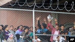 FILE - In this March 27, 2019, photo, Central American migrants wait for food in a pen erected by U.S. Customs and Border Protection to process a surge of migrant families and unaccompanied minors in El Paso, Texas. 